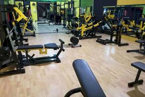 Fitnessstudio mit verschiedenen Trainingsgeräten wie Hanteln und Kraftmaschinen.