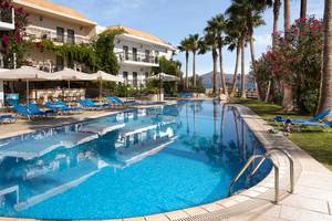 Pool neben dem Almyrida Beach Hotel mit Sonnenliegen und Palmen.
