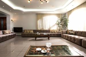 Wohnzimmer mit drei Sofas, einem Couchtisch und einer Lampe, alles in einem hellen Raum