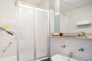 Badezimmer im Remisens Hotel Albatros mit Dusche, Spiegel und Waschbecken.