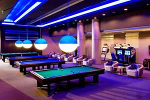 Spielzimmer im Gloria Verde Resort mit Billardtischen, Spielkonsolen und Sitzmöbeln.