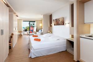 Doppelbett mit weißen Laken und orangenen Handtüchern im Schlafzimmer des Be Live Experience Lanzarote Beach Hotels.