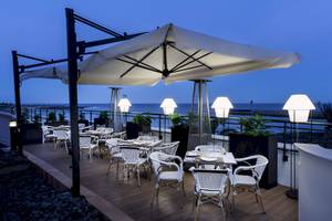 Außenterrasse des Be Live Experience Lanzarote Beach Hotels bei Nacht mit Tischen und Stühlen unter einem großen Schirm.