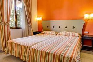 Doppelbett im Hotelzimmer im SBH Taro Beach mit orangefarbenen Wänden und gestreiften Bettdecken.