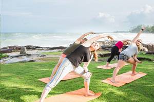 Yoga-Kurs am Strand im Khao Lak Laguna Resort mit vier Frauen, die Yoga-Posen ausführen.