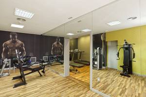 Fitnessstudio im Olympic Palace Resort mit Spiegelwänden und Trainingsgeräten.