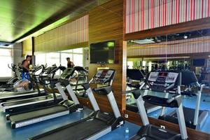 Fitnesscenter im Side Crown Palace Hotel mit Laufband, Fernseher und Spiegeln.