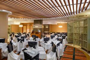 Das elegante Restaurant des Side Crown Palace mit gedeckten Tischen und hängenden Vorhängen.