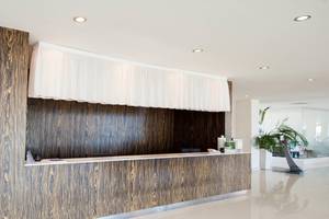 Die Rezeption des Vrissiana Beach Hotels mit einer Holzwand und einer weißen Stoffabdeckung.