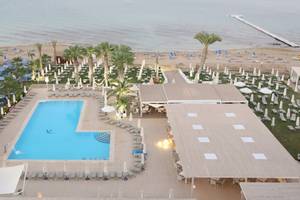 Luftaufnahme des Vrissiana Beach Hotels mit Pool, Liegestühlen und Gebäuden am Strand