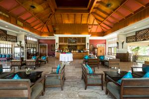 Lobby des Fair House Beach Resorts mit Holzdecken, Empfangstresen und blauen Kissen auf den Stühlen.