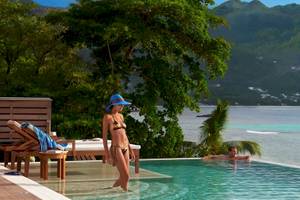 Ein Paar schwimmt im Außenpool des Hilton Seychelles Northolme Resort & Spa mit Blick auf das Meer.