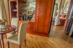 Innenansicht eines Hotelzimmers mit Esstisch, Obstschale und Weinflasche.