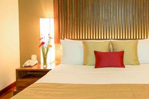 Hotelzimmer im Occidental Eden Beruwala mit Bett, Kissen, Nachttischen und Dekoration.