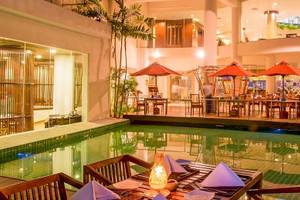 Pool-Lounge im Occidental Eden Beruwala Hotel mit roten Sonnenschirmen und Tischen.