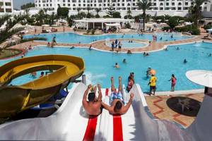 Ein Schwimmbad im El Mouradi Hammamet Hotel mit Wasserrutsche und vielen Gästen.
