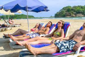 Mehrere Gäste liegen auf Sonnenliegen am Strand des Occidental Eden Beruwala.