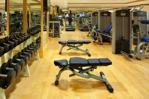 Fitnessstudio im Grand Hyatt Muscat mit verschiedenen Trainingsgeräten und einer Person, die ein Laufband benutzt.