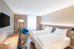 Zimmer im NH Hamburg Altona Hotel mit zwei Betten, Schreibtisch und Fernseher.