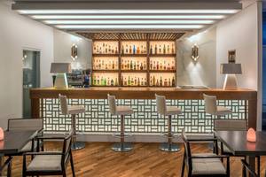 Innenansicht der Bar im Mediterranean Beach Hotel in Zypern mit einer Theke, mehreren Barhockern und einer Auswahl an Getränken.