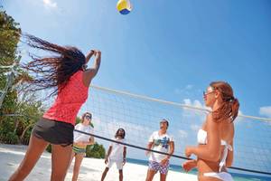 Volleyballspiel am Strand des Malahini Kuda Bandos Resorts mit Teilnehmern in Sonnenbrillen.