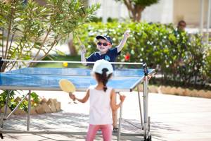 Zwei Kinder spielen Tischtennis im Freien im El Mouradi Hammamet Hotel.