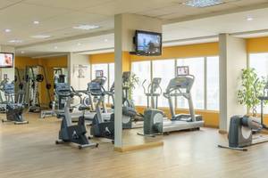 Fitnessstudio im Tower Plaza Hotel Dubai mit vielen Geräten und Fernsehern an der Wand.