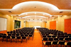 Ein Konferenzraum im El Mouradi Hammamet Hotel mit Reihen von Stühlen und einer Bühne.