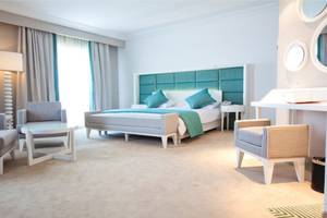 Schlafzimmer im El Mouradi Hammamet Hotel mit einem Bett, zwei Sesseln, einem Tisch und einer Lampe.
