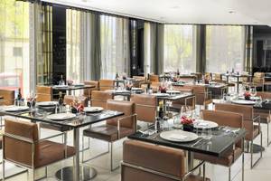 Foto des Innenbereichs des Restaurants im H10 London Waterloo Hotel mit gedeckten Tischen und Stühlen.