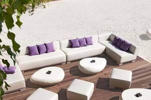 Loungebereich am Strand des Constance Moofushi Maldives Hotels mit weißen Möbeln und Kissen.