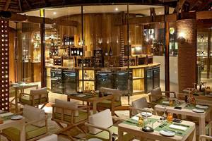 Innenansicht des Restaurants im Constance Moofushi Maldives, mit Tischen, Stühlen und Bar.