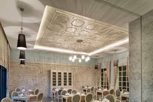 Innenansicht des Restaurants im Aska Lara Resort & Spa mit Tisch, Stühlen und dekorativen Deckenleuchten.