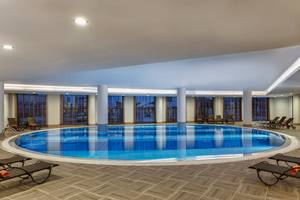 Innenpool des Aska Lara Resort & Spa mit Liegestühlen und Panoramafenstern