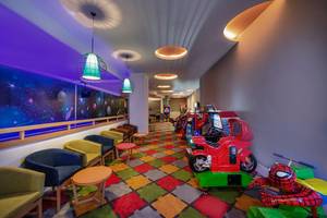 Spielbereich im Aska Lara Resort & Spa mit bunten Spielgeräten und Sofas.