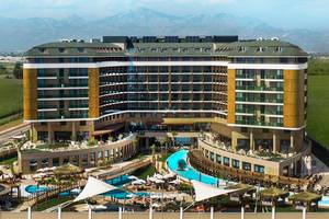 Außenansicht des Aska Lara Resort & Spa mit Swimmingpools und Bergen im Hintergrund.