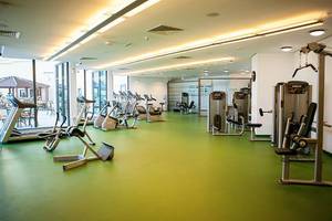 Fitnesscenter im JA Ocean View Hotel mit grünem Boden und vielen Trainingsgeräten.