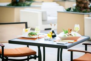 Gedeckter Tisch auf der Terrasse des JA Ocean View Hotels mit Salat, Öl und Getränken.