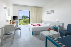 Zimmer im Aeolos Beach Hotel mit Herz-Dekoration auf dem Bett und Blick auf den Garten.
