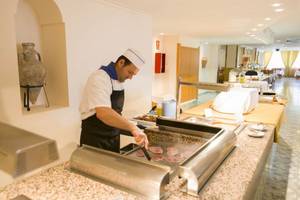 Ein Koch bereitet Fleisch im Restaurant des Moon Dreams Coral Beach Hotels zu.