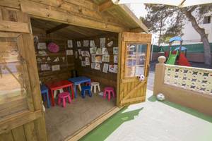 Ein Spielzimmer im Hotel Moon Dreams Coral Beach mit bunten Tischen, Stühlen und Kinderzeichnungen an der Wand.