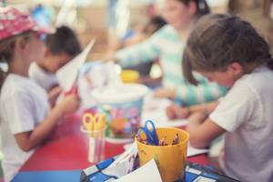 Kinder basteln bei Moon Dreams Coral Beach an einem Tisch mit bunten Malutensilien und Papier.