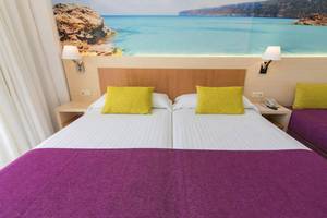 Doppelzimmer im Hotel Moon Dreams Coral Beach mit bunten Kissen und Meerblick-Wanddekoration.