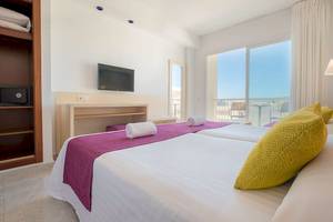 Helles Hotelzimmer im Moon Dreams Coral Beach mit zwei Betten, Fernseher und Fenster mit Meerblick.