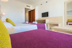 Gemütliches Zimmer im Moon Dreams Coral Beach mit zwei Betten, Fernseher und minimalistischer Einrichtung.