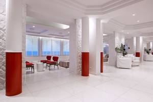 Innenbereich des Dimitra Beach Hotel & Suites mit weißen Böden, roten Säulen und Blick aufs Meer