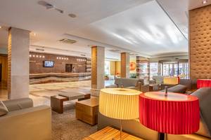 Empfangsbereich des Zafiro Tropic Hotels mit Rezeption, Sofas und Lampen.