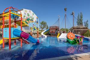 Wasserspielplatz des Zafiro Tropic Hotels mit bunten Rutschen und einem Piratenschiff im Hintergrund