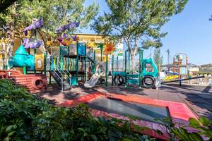 Spielplatz im Freien im Zafiro Tropic Hotel mit bunten Spielgeräten und einem Trampolin.