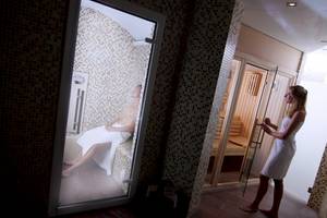 Eine Frau steht in der Tür einer Sauna, während ein Mann auf einer Bank darin sitzt, beide im Zafiro Tropic Hotel.